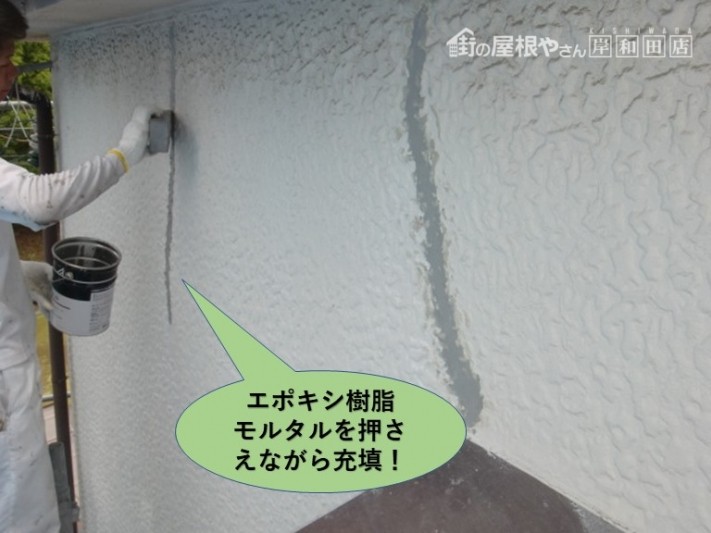 岸和田市の外壁のひび割れにエポキシ樹脂モルタルを押さえながら充填します