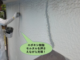 岸和田市の外壁のひび割れにエポキシ樹脂モルタルを押さえながら充填します