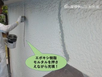 岸和田市の外壁のひび割れにエポキシ樹脂モルタルを押さえながら充填します