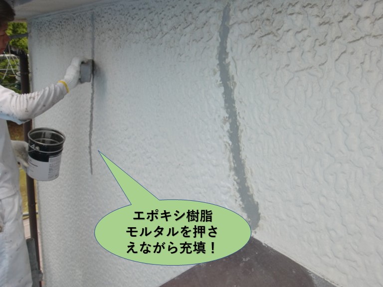 岸和田市の外壁のひび割れにエポキシ樹脂モルタルを押さえながら充填します